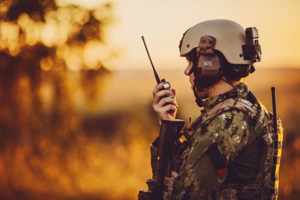Soldier in a field at sunset using a radio